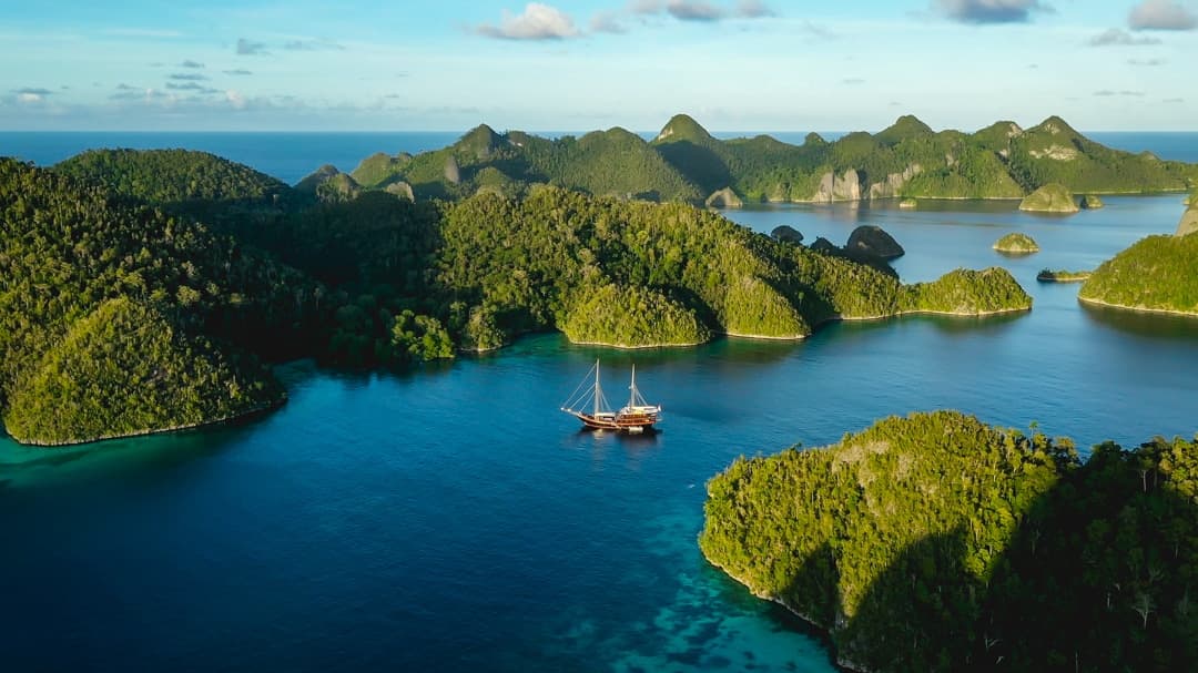 Dunia Baru at anchor among the green karst islands and lagoons of Raja Ampat