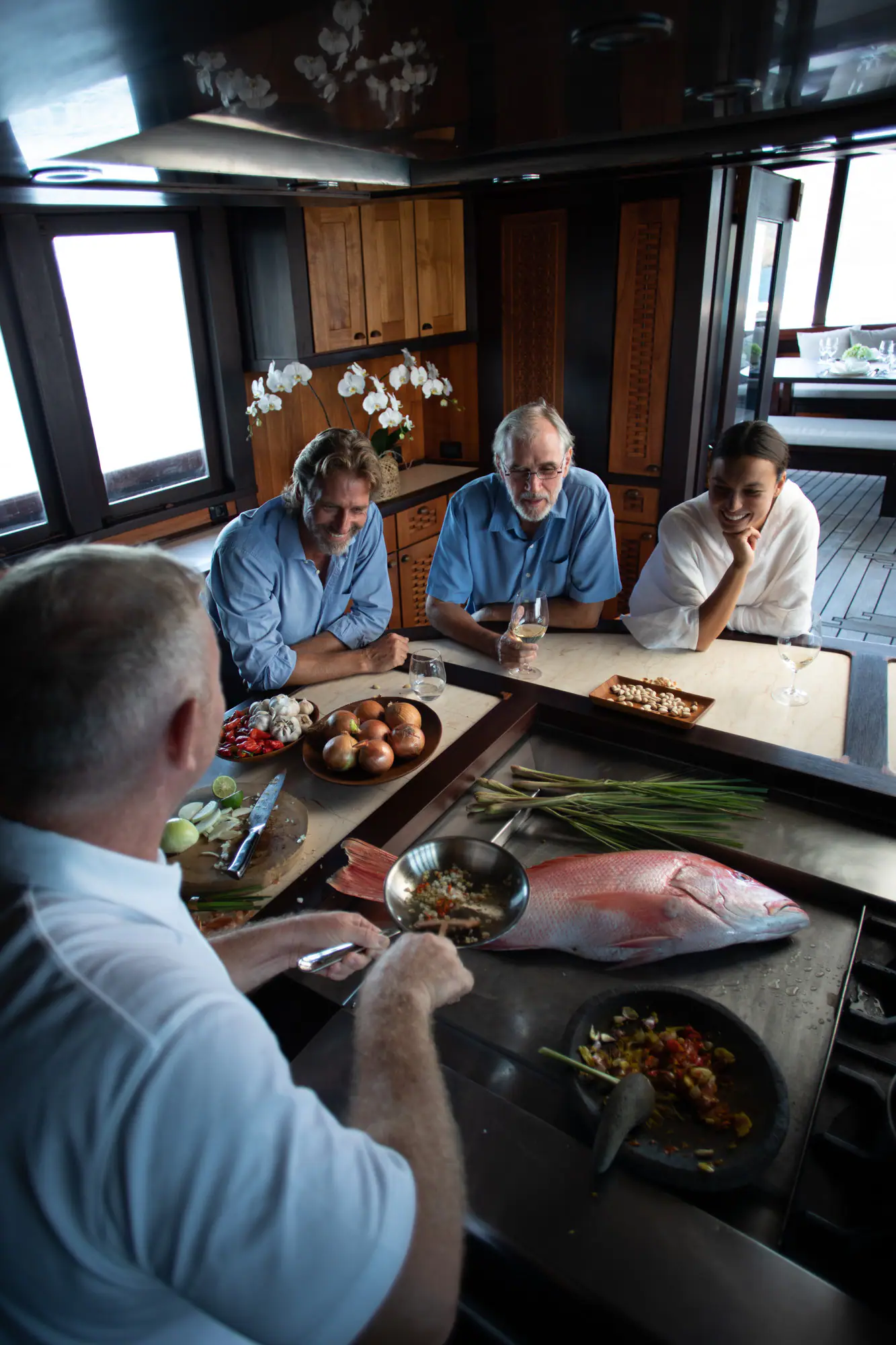 Guests at the counter of Dunia Baru's open kitchen, watching the chef prepare fresh seafood