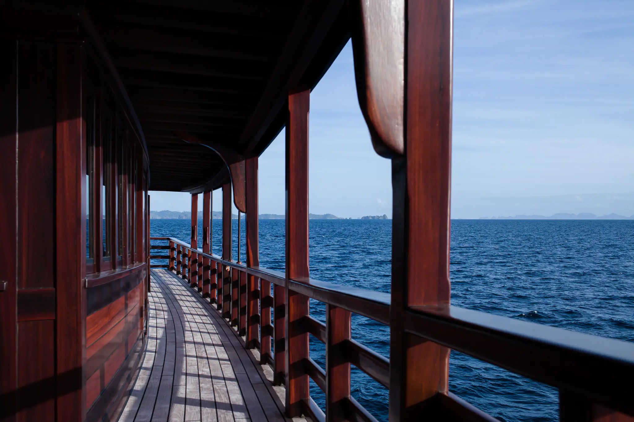 Dunia Baru's teak side deck and hand-finished railings running aft beside the open sea
